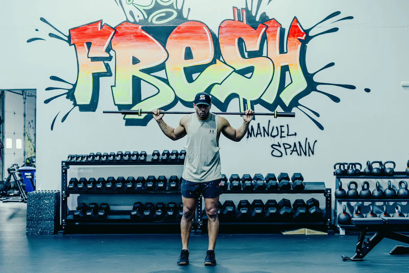 An athlete with the Melo Bar across his shoulders in front of the FRESH mural.